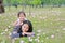 Happy Asian mother and her daughter cuddle lying on green field with fully fall pink flower in the garden outdoor