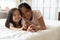 Happy Asian mother lying in bed together with small daughter