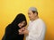 Happy Asian muslim couple doing greeting gesture, apologize and forgiving each other on eid mubarak tradition, against yellow