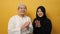 Happy Asian muslim couple doing hand clap applause gesture, against yellow