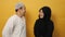 Happy Asian muslim couple looking each other and smiling, husband and wife love romance relationship over yellow