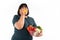 Happy Asian overweight woman Eating, holding a vegetable basket, and smiling on isolated white background, Concept of good health