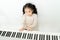 Happy Asian preschooler playing piano in house