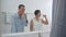 Happy asian senior adult couple brushing teeth in clean white bathroom. Elderly grandmother and grandfather doing morning hygiene.