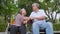 Happy Asian senior couple sitting in wheelchair and old woman holding husband hands and talking together and relaxing outdoors in