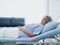 Happy Asian senior woman patient grey hair smiling and looking at camera while lying on bed in hospital.