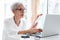 Happy asian senior woman working,surfing the internet with laptop computer at table in home,smiling elderly people in glasses with