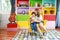 Happy asian single mother and son sitting on sofa in colorful modern living room with smiling face while playing magnifying