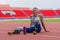 Happy Asian speed runner, with two prosthetic running blades, enjoys a restful moment on the stadium track after a rigorous speed