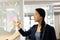 Happy asian woman brainstorming and writing on glass board in office