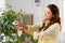 Happy asian woman cleaning houseplant