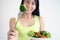 A happy Asian woman with a healthy salad dish, holding fork with a large broccoli. Food for good shape