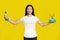 Happy asian woman sideways stretched cable of old fashion telephone looking at camera isolated on yellow background