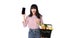 Happy Asian woman with smartphone holding basket full of fresh vegetable groceries isolated on white background