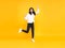 Happy Asian woman smiling and jumping while celebrating success isolated over yellow background