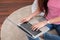 Happy asian woman typing on laptop computer at home.female freelancer sitting on carpet on floor work at home in living room