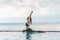 Happy Asian woman wearing black sport wear practice yoga Pigeon pose on the pool above the beach with beautiful sea