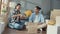 Happy asian young attractive couple man and woman sit at new home drink coffee relax and talk smile with carton package box