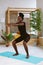 Happy athletic afro american woman with smile squatting with arms extended forward, training on gymnastic mat in