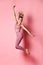 Happy athletic woman jumping in silhouette. Photo of sporty woman in fashionable pink sportswear on pink