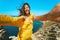 Happy atractive taned woman making selfie and smile to the camera on cliff edge with beautiful sea view.