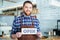 Happy attactive young barista holding open sign at coffee shop