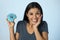 Happy attractive Latin woman smiling excited holding sugar donut on clear background in sugar abuse