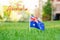 Happy Australia Day card with greeting text. Australian flag standing on green grass in front of house. Australia day national