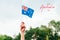 Happy Australia Day card with greeting text. Closeup of woman human hand arm waving Australian flag against blue sky. Proud