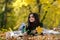 Happy autumn teenage girl having fun with leaves outdoor in park.