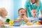 Happy babies in day care. Group of kids playing toys with kindergarten teacher. Children lesson in creche