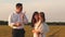 Happy baby blows a kiss to mom and dad. A child kisses a beloved mother and father walking in a field in the sun. Happy