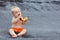 Happy baby boy eating orange papaya fruit on black beach