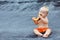 Happy baby boy eating orange papaya fruit on black beach