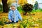 Happy baby boy among fallen leaves in autumn park