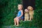 Happy baby boy sitting with two golden labrador retriever puppies