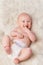 Happy baby, diaper and laugh in bedroom, furry blanket and playtime in cute for child development. Infant, kid and