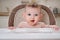 Happy baby with food stained mouth sitting on child chair, home kitchen background