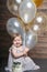 Happy baby girl with air balloons and cake on birthday party