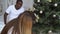 Happy baby girl hanging ball on a Christmas tree. Children decorating a Christmas tree. Young happy multi-ethnic family