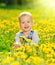 Happy baby girl on meadow with yellow flowers on