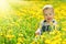 Happy baby girl on meadow with yellow flowers on the nature