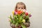 Happy baby girl rejoices and smiles with a bouquet of multi-colored tulips in hands