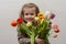 Happy baby girl rejoices and smiles with a bouquet of multi-colored tulips in hands