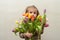 Happy baby girl rejoices and smiles with a bouquet of multi-colored tulips in hands