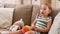 Happy baby girl sitting on sofa with toys at home