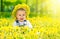 Happy baby girl in a wreath on meadow with yellow
