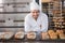 Happy baker standing near tray with bread