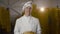 Happy baker in uniform holds a fresh loaf of a bread in a bakery with backlit