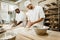 happy bakers kneading dough together at baking manufacture